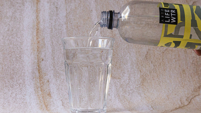 pouring water into glass from LIFEWTR bottle