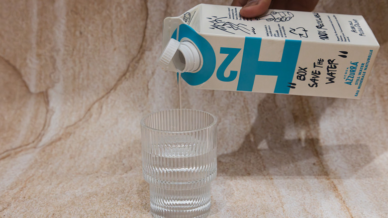 Hand pouring H2O water into glass