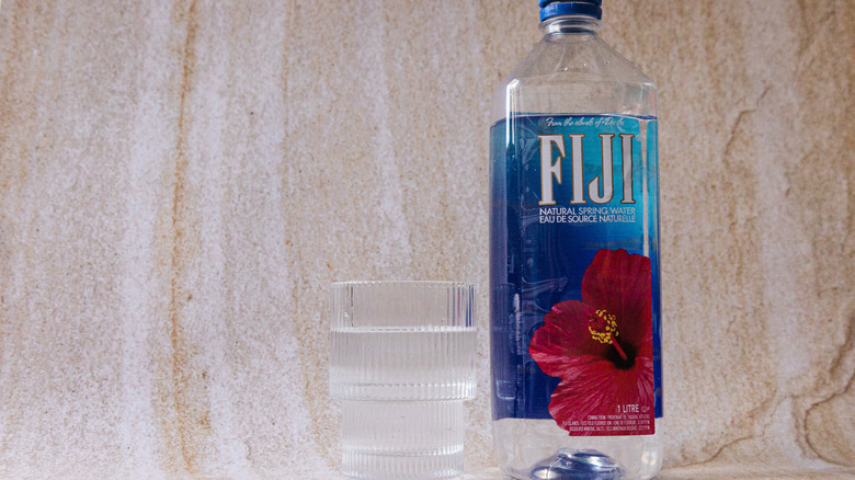 FIJI Water next to glass cup