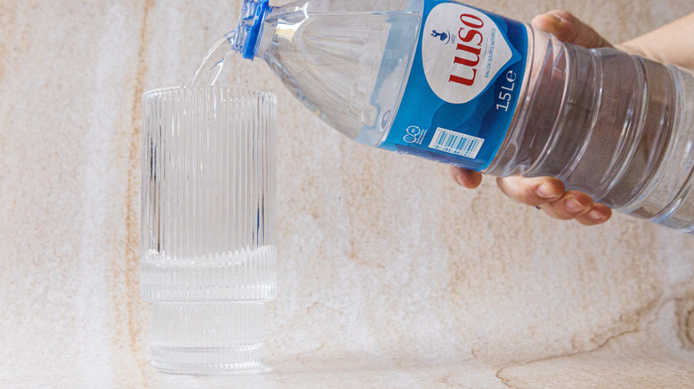 Pouring Agua de Luso into glass cup