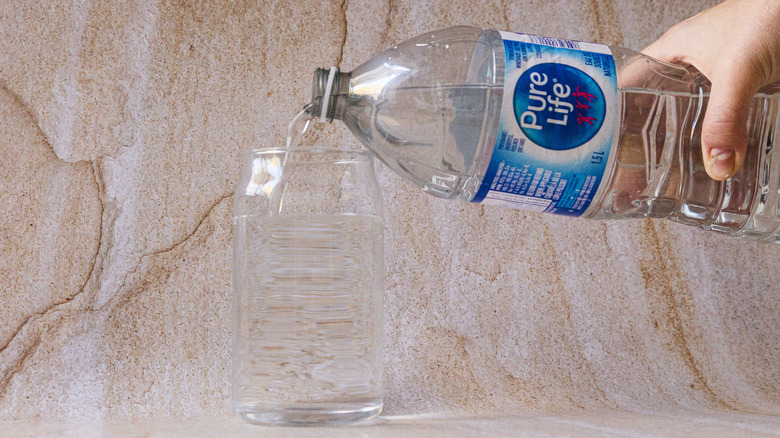 Pouring Pure Life water into glass from bottle