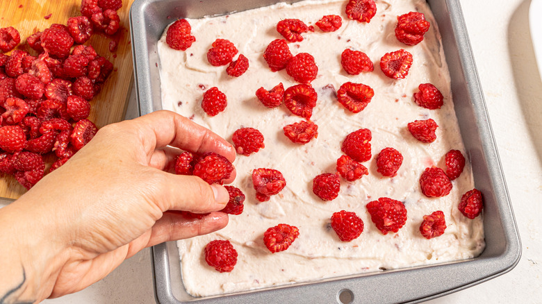 Adding fresh raspberries on top of spread out mascarpone