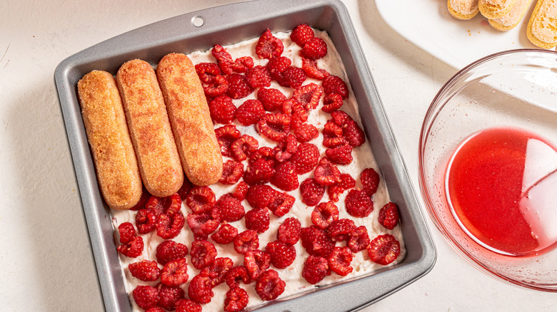 Arranging ladyfingers on top of fresh raspberries