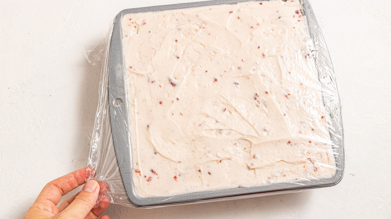 Covering raspberry tiramisu dish with plastic wrap