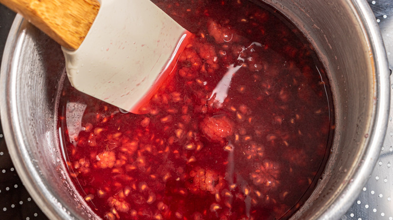 Broken down raspberries in syrup in a saucepan