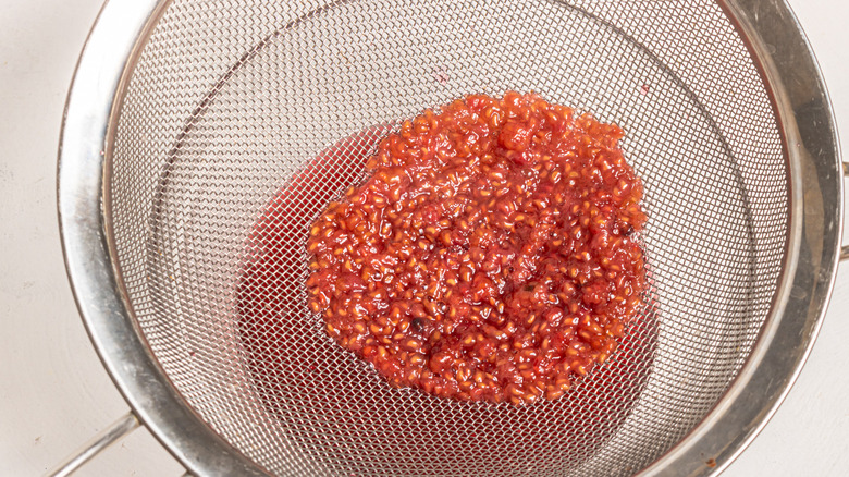 Straining raspberries through a sieve