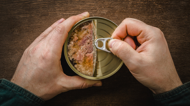 hands opening canned chicken