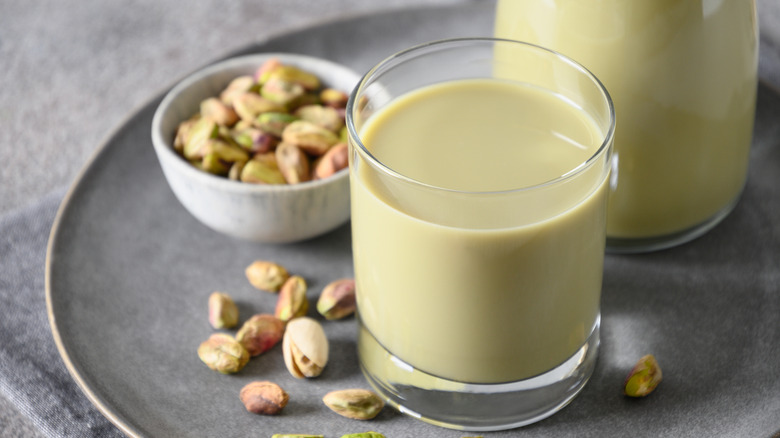 Pistachio milk in a glass with a bowl of pistachios next to it