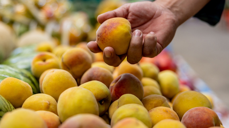Person choosing peach at market