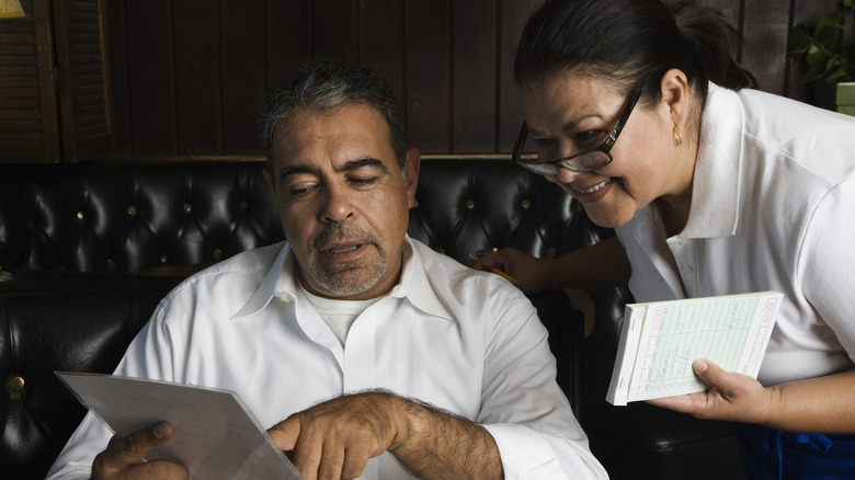 Server and diner reviewing a menu