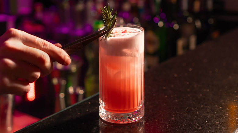 Bartender adding fresh herbs to cocktail