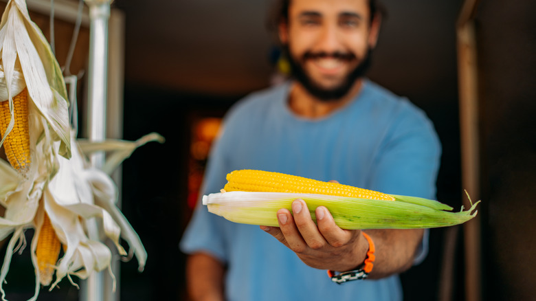 man holding corn on the cob