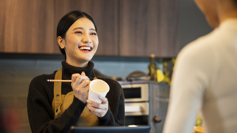 Coffee shop owner writing customer name on cup while smiling at customer