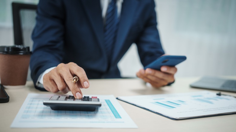 Man in suit at desk working with calculator