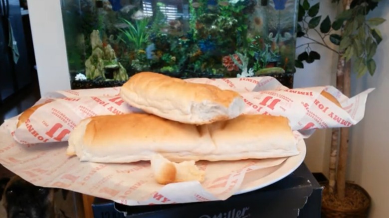 Day-old bread from Jimmy John's, one loaf is wrapped and the other is unwrapped and broken in half