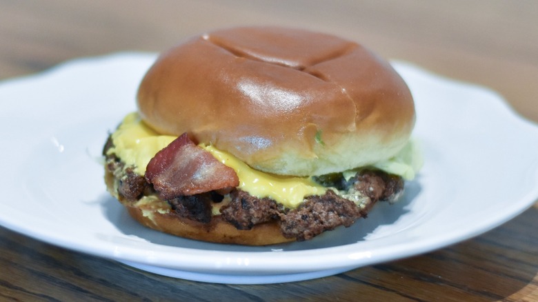 A bacon cheeseburger on a white plate