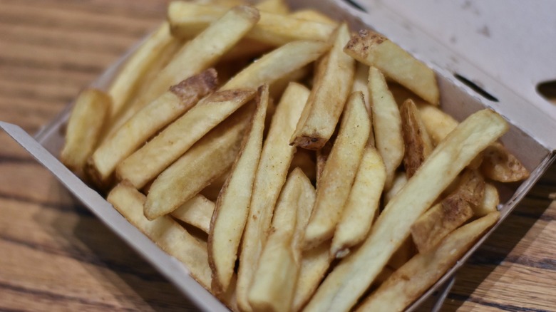 An open box of french fries on a wooden table