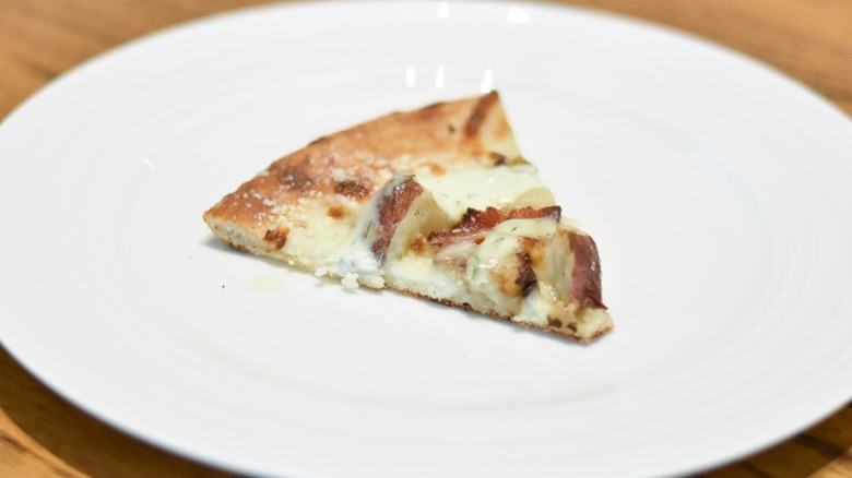 A slice of potato pizza on a white plate