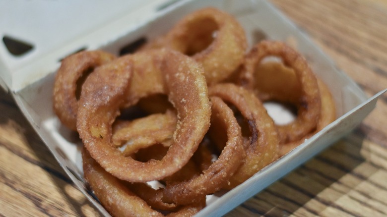 An open box of onion rings on a wooden table