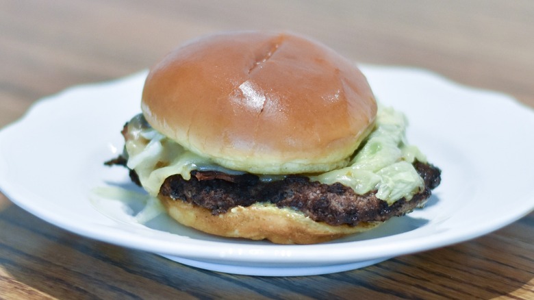 A burger with white cheese on a white plate