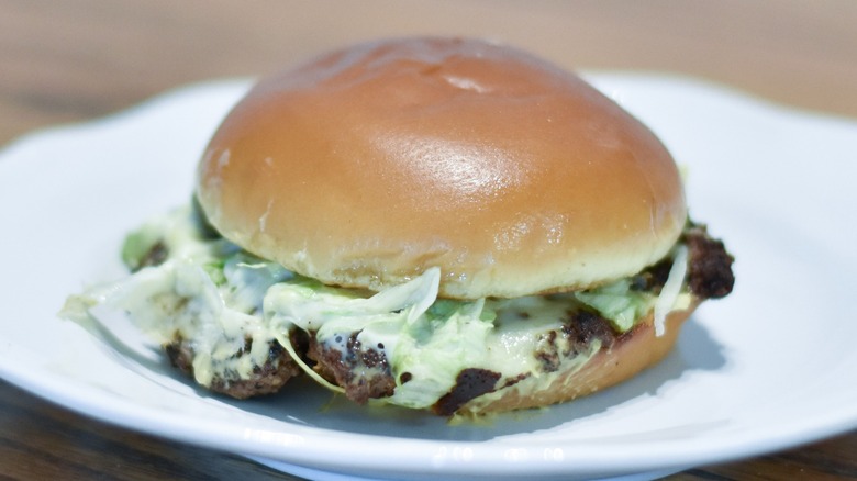 A burger with cheese and lettuce on a white plate