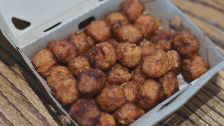 An open box of sweet potato tots on a wooden table