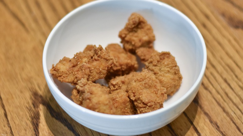 A white bowl of boneless chicken wings on a wooden table