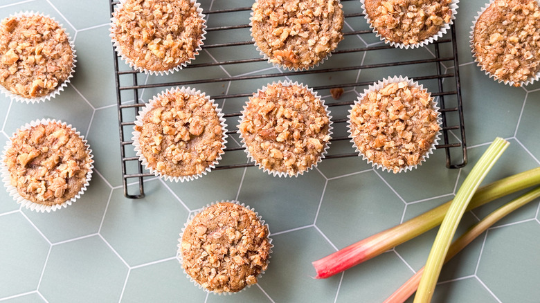 Rhubarb and cardamom oat muffins on cooking rack with rhubarb stalks