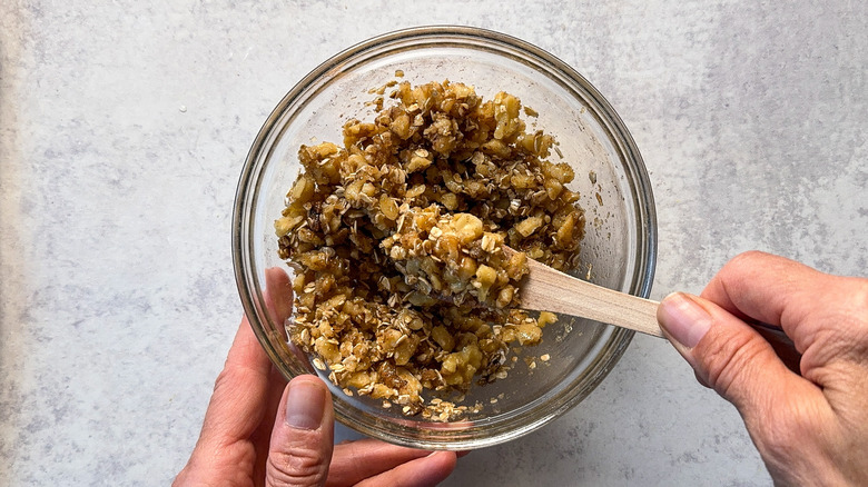 Mixing walnut oat streusel in glass bowl with wooden spoon