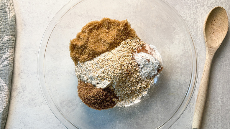 Dry ingredients for rhubarb and cardamom oat muffins in glass bowl on countertop