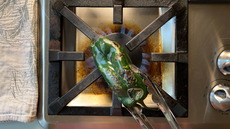 Poblano pepper over gas flame with tongs