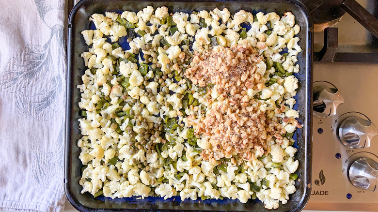 Chopped cauliflower, poblano peppers, walnuts, capers on baking sheet
