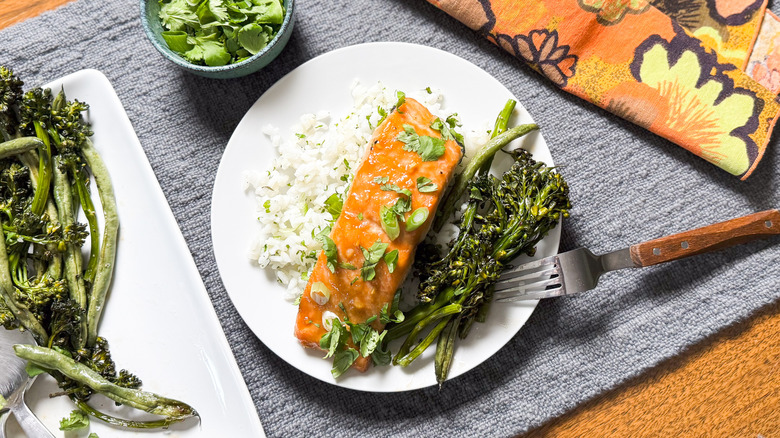 Roasted miso maple salmon with cilantro rice and roasted broccolini and green beans on plate with fork and napkin