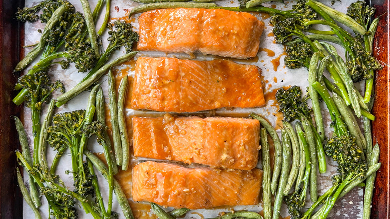 Roasted miso maple salmon with broccolini and green beans on parchment-lined baking sheet