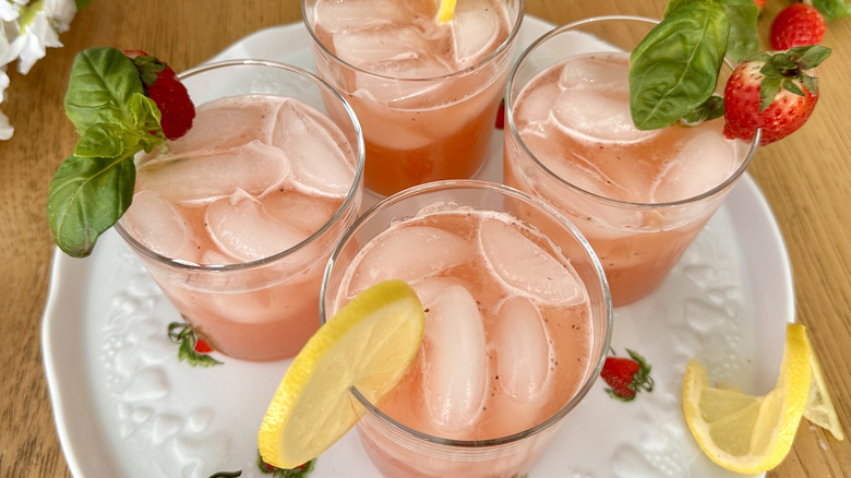pink lemonade garnished with lemon slices, strawberries and basil