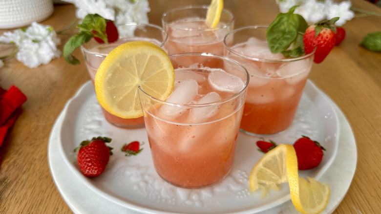 pink lemonade garnished with lemon slices, strawberries and basil