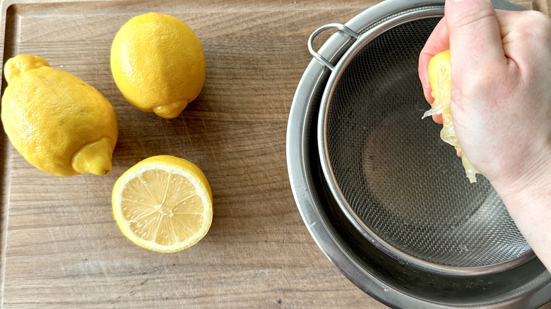 hand stirring squeezing a lemon into a strainer