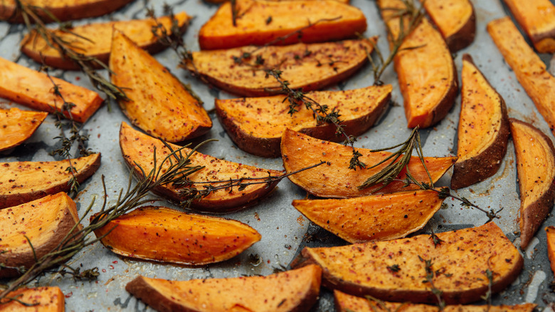 Roasted sweet potatoes with herbs on baking sheet