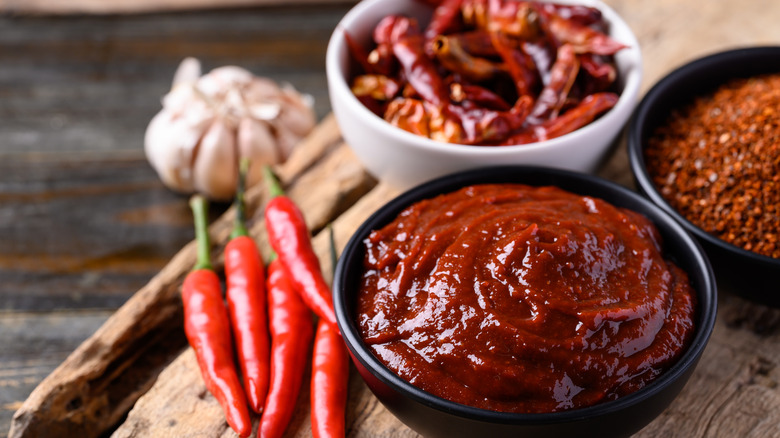 Bowl of gochujang alongside chile peppers