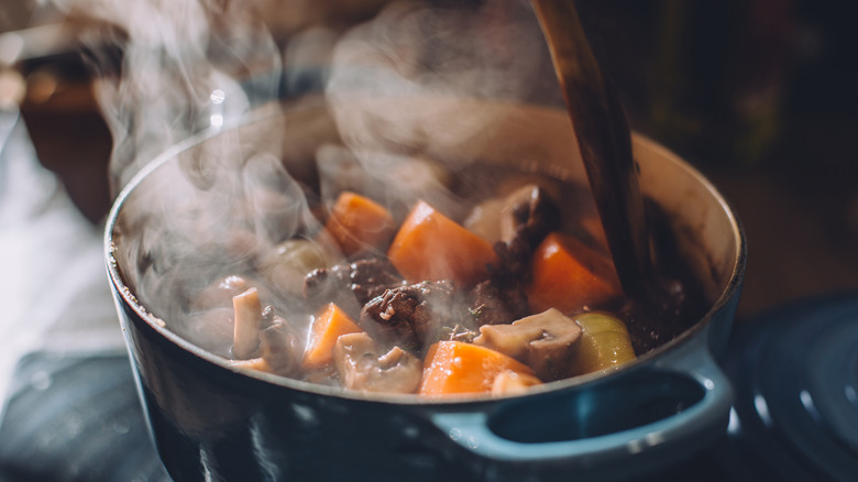 A beef stew cooking in a large pot on a stove