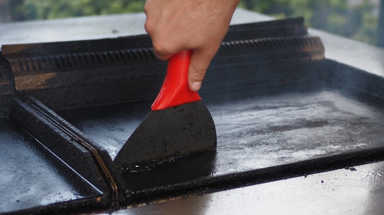 Metal scraper cleaning a flat-top