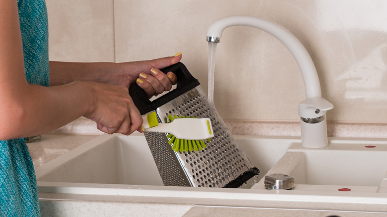 A woman cleaning a cheese grater