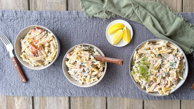 Salmon dill pasta salad in serving bowl with dill frond garnish