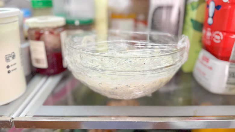 Salmon dill pasta salad sauce in covered glass bowl in refrigerator