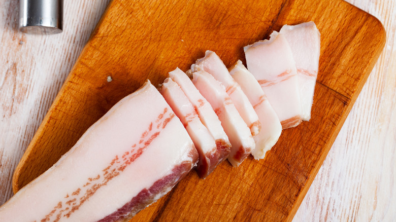 Salted pork belly on a piece of wood.