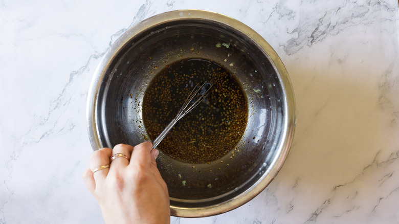 hand mixing marinade in metal bowl