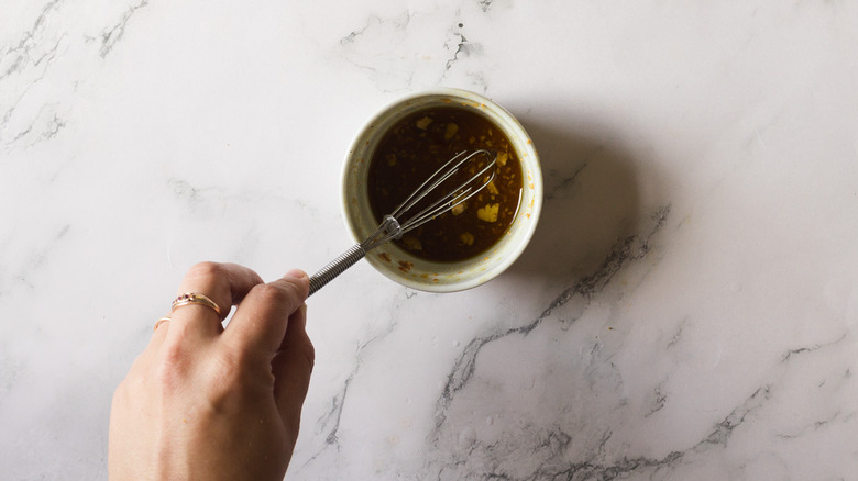 Hand whisking small bowl with marinade