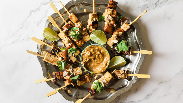 Satay tofu skewers with toppings on metal plate