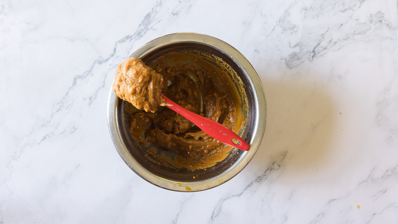 adding peanut butter to metal bowl