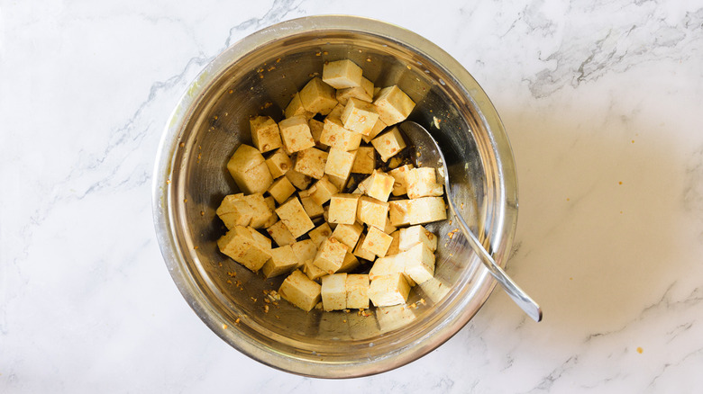 tofu in marinade in metal bowl